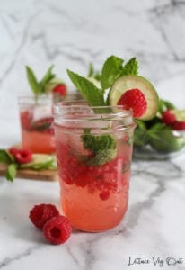 Raspberry mojito mocktail in small mason jar and mint, lime raspberry garnishes
