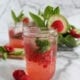 Raspberry mojito mocktail in small mason jar and mint, lime raspberry garnishes