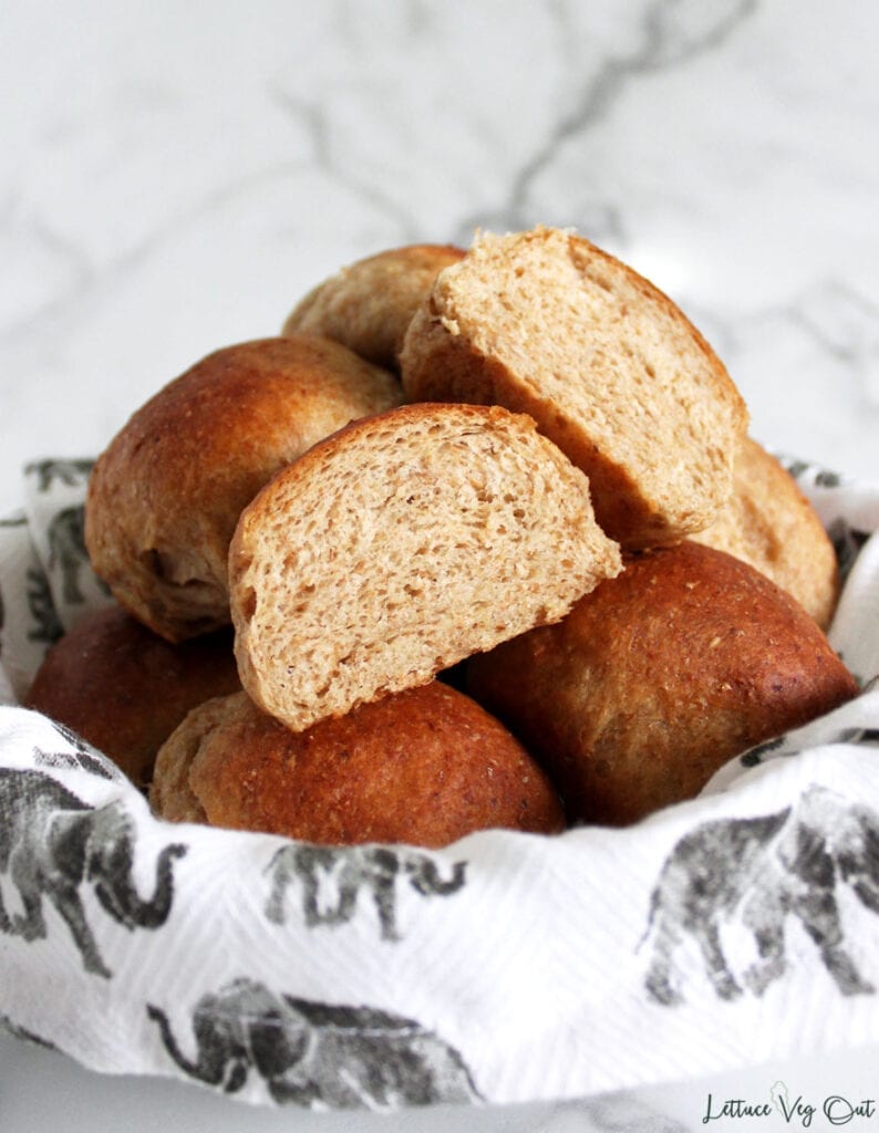 Bowl of whole wheat vegan dinner rolls with one cut in half