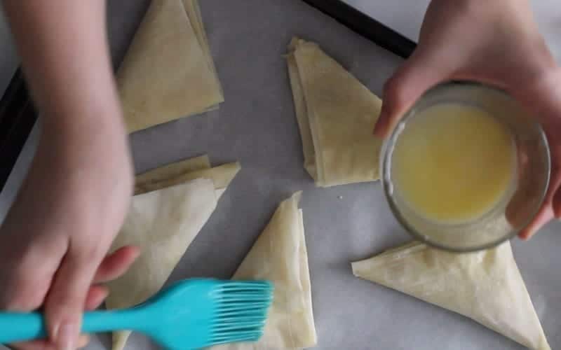 Image of brushing vegan butter on top of phyllo pastry to create a flaky, flavorful vegan apple turnover