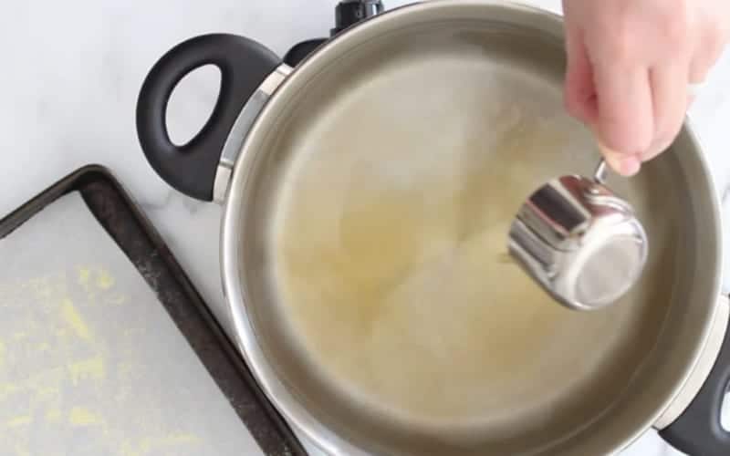 Image of water bath needed to form a crusty outer layer for homemade vegan bagels; maple syrup being poured into the pot.