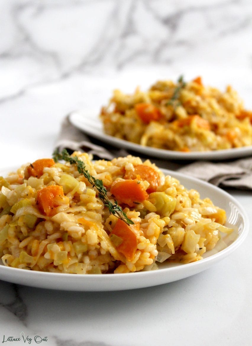 Two plates of vegan pumpkin leek risotto with creamy chunks of pumpkin showing through the arborio rice