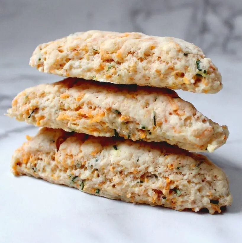 Stack of three vegan cheese and chive scones set on marble background