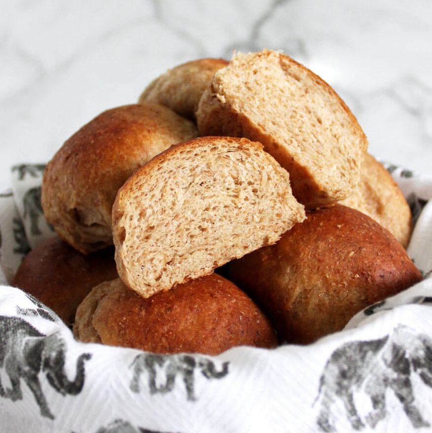 Bowl of whole wheat vegan dinner rolls with one cut in half