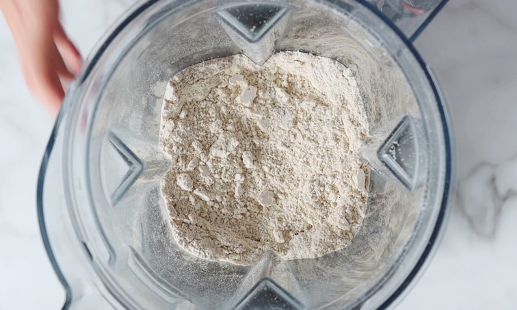Top view of a blender filled with powdery oat flour.