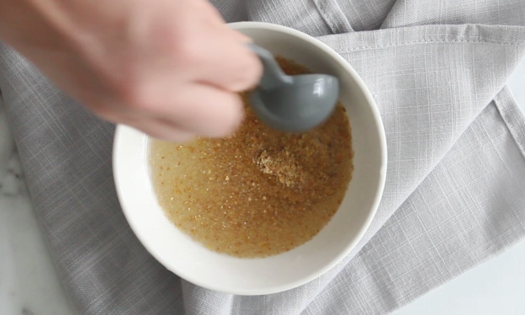 Top view of a small bowl sitting on a folded grey towel. Bowl filled with water and ground flaxseed being stirred.