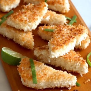 Wood board topped with triangle-shaped coconut-crusted tofu pieces.