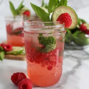 Small mason jar filled with pink raspberry, lime and mint mocktail.
