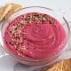 Close up of glass dish filled with pink beetroot dip.