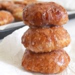 Close up of a stack of 3 apple fritters with glaze dripping down edges.