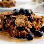 Close up of a slice of blueberry baked oatmeal topped with peanut butter and fresh blueberries.
