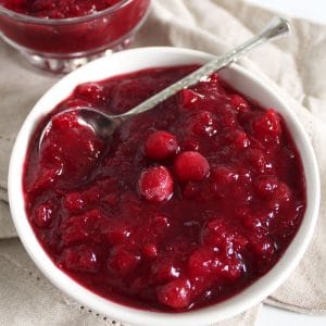 Close up of a small white bowl of cooked cranberry apple sauce.