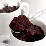 Close up of a spoonful of microwave brownie resting on a white mug.