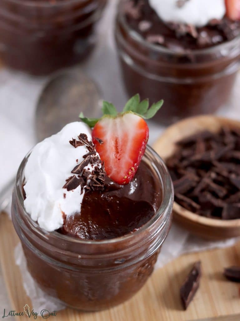 Close up of a jar of chocolate avocado pudding with a bite scooped out.