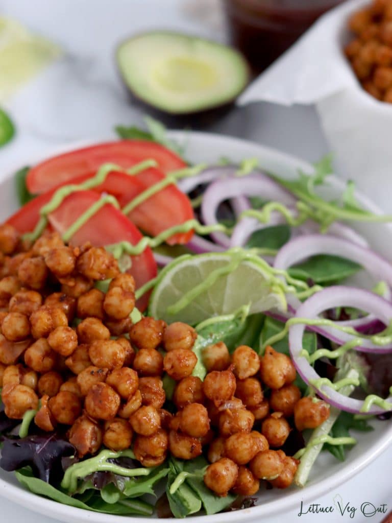 Close up of a plate of salad that is half covered with barbecue chickpeas.