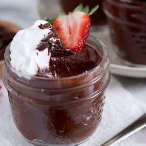 Close up of small jar of chocolate pudding with bite scooped out.