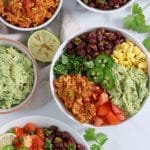 Close up of burrito bowl with Mexican-rice, spiced black beans, guacamole, corn and tomatoes.