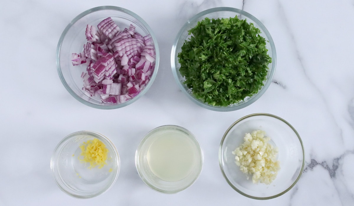 Small dishes of prepped falafel ingredients (red onion, parsley, lemon zest, lemon juice, garlic).