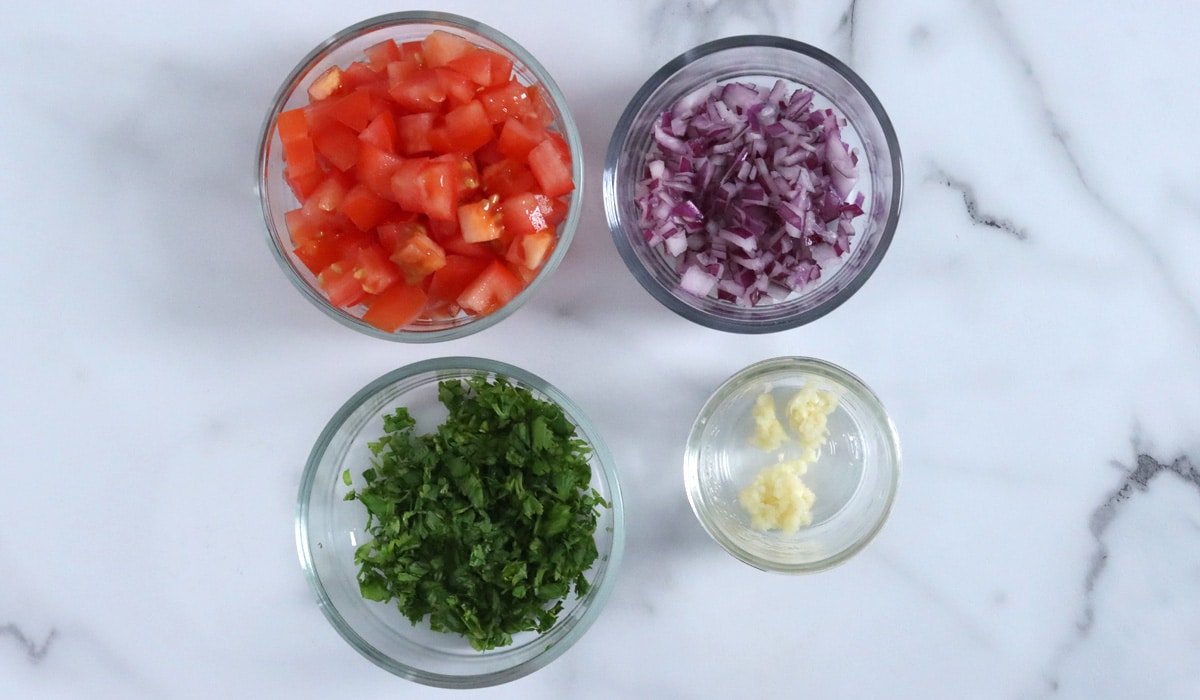 Prepped ingredients for bean and corn salsa (chopped tomato, onion, cilantro and garlic).