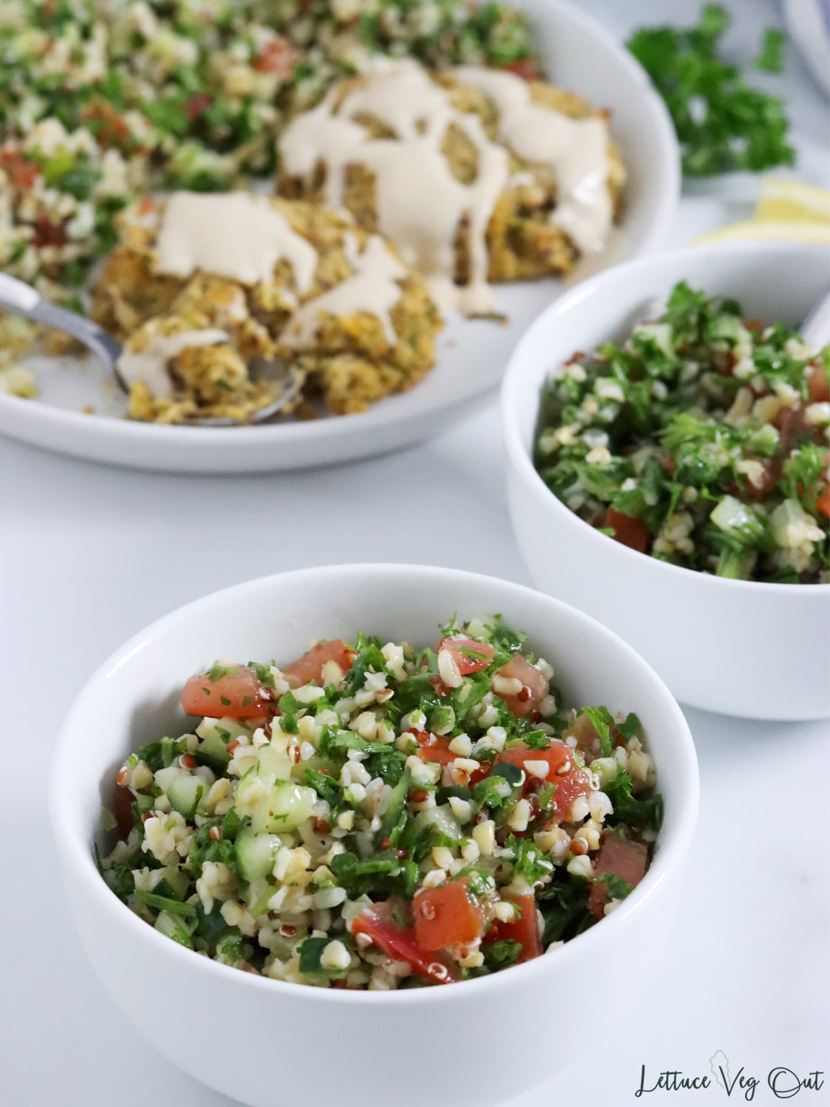 Two small bowls of tabbouleh salad (bulgur, parsley, tomato, onion) with plate of falafel in back.