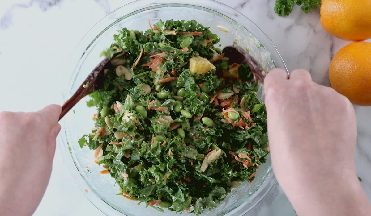 Tossing kale salad in large bowl.