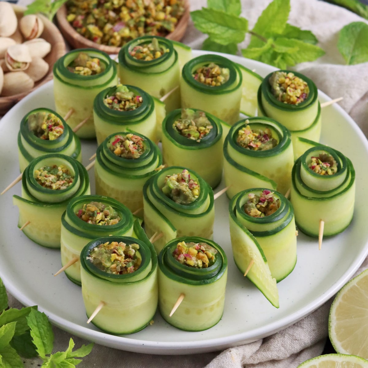 Close up of plate filled with cucumber rollups filled with pistachio and avocado.