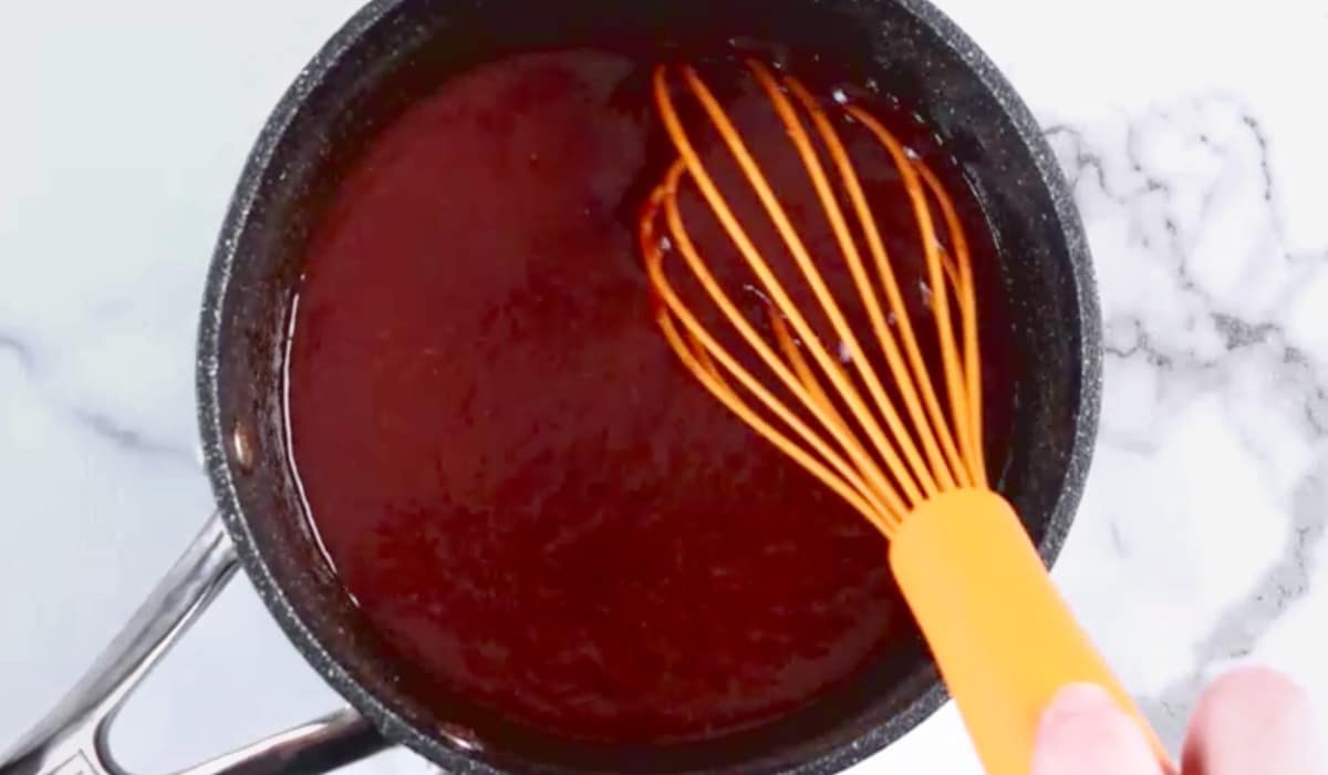 Whisking cooked barbecue sauce in pot.