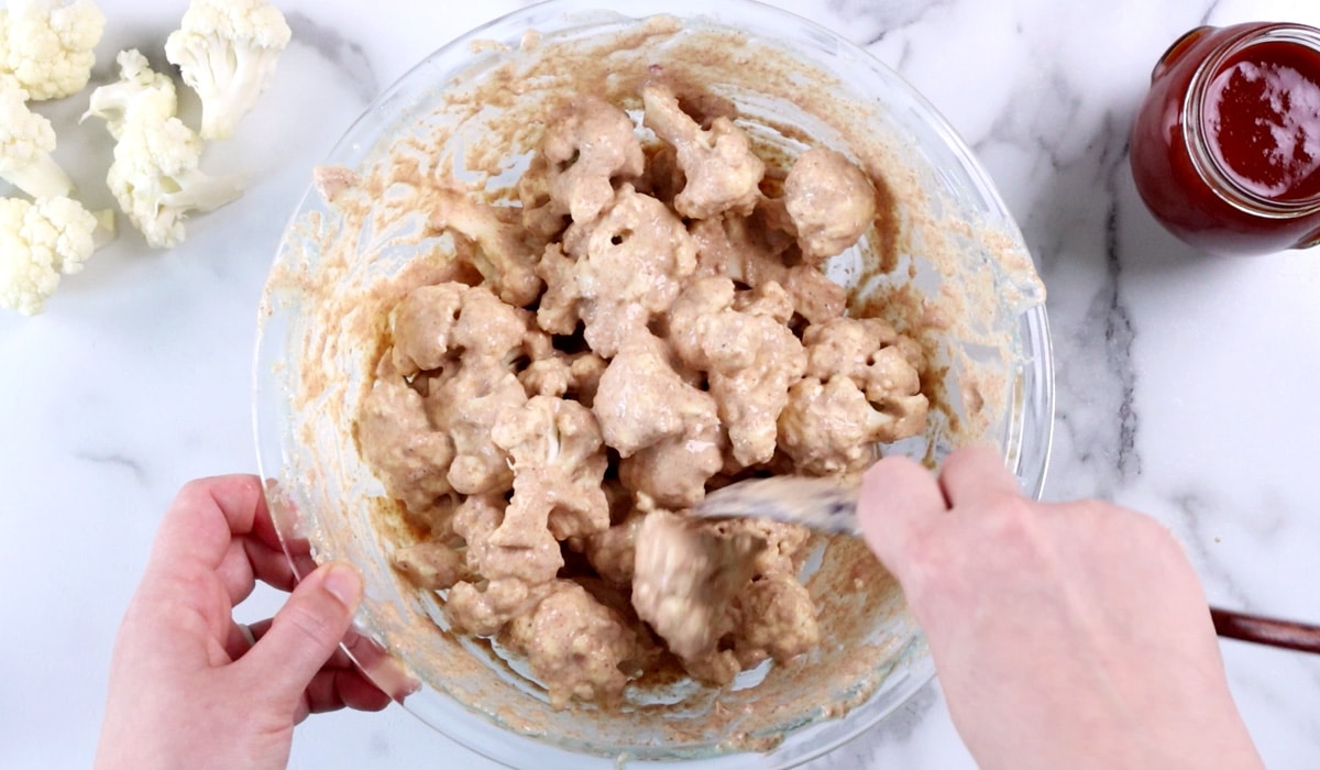 Tossing cauliflower pieces in spiced batter.