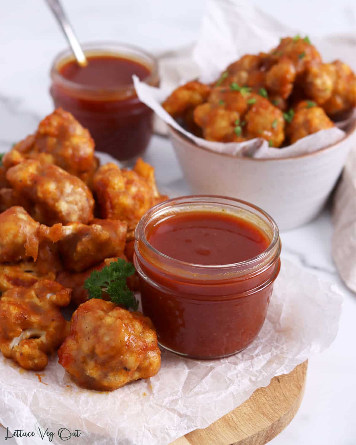 Jar of BBQ sauce surrounded with cauliflower bites.