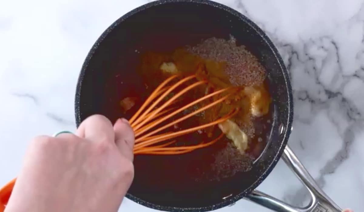 Whisking barbecue sauce ingredients in pot.