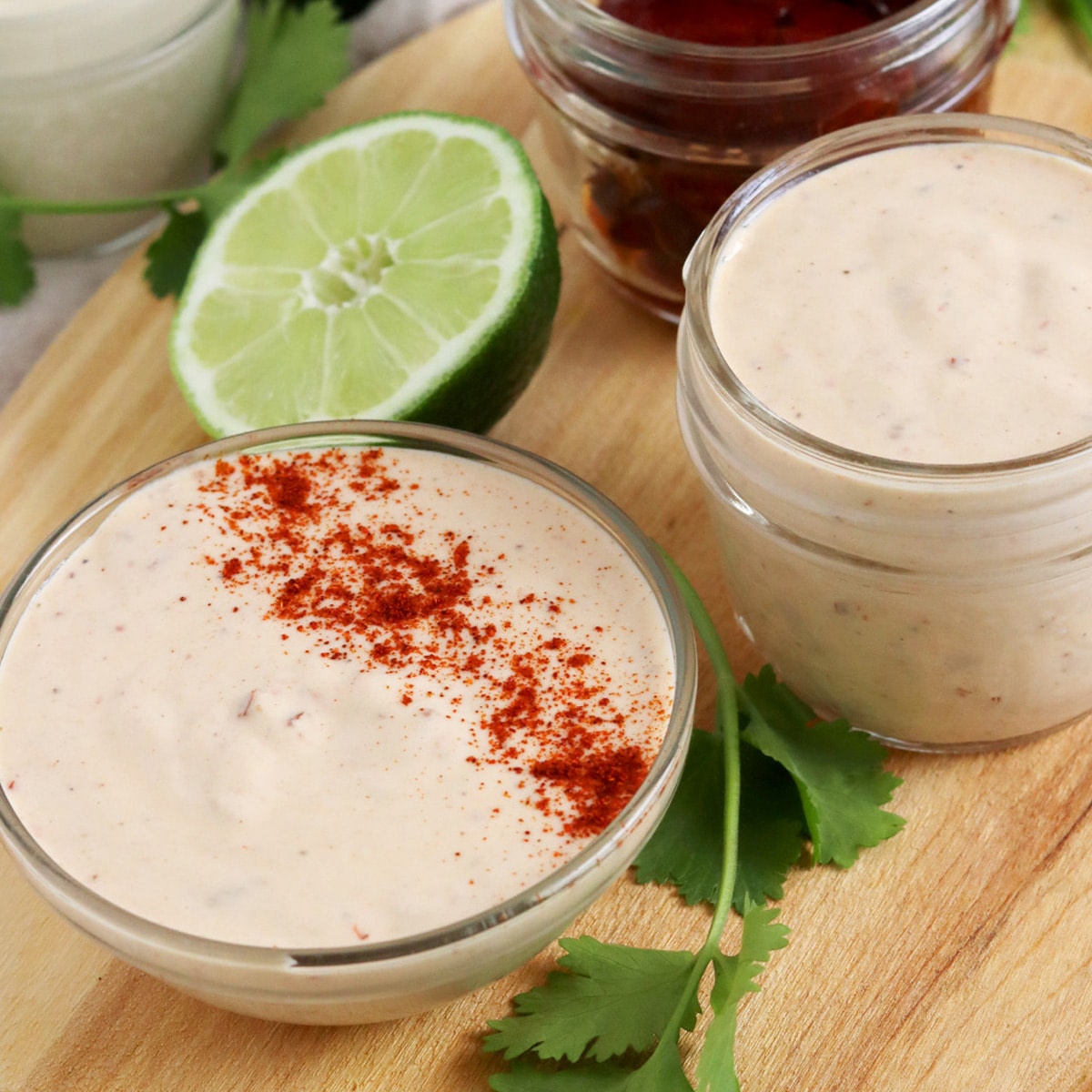 Close up of two jars of chipotle mayo with paprika garnish and a lime slice.