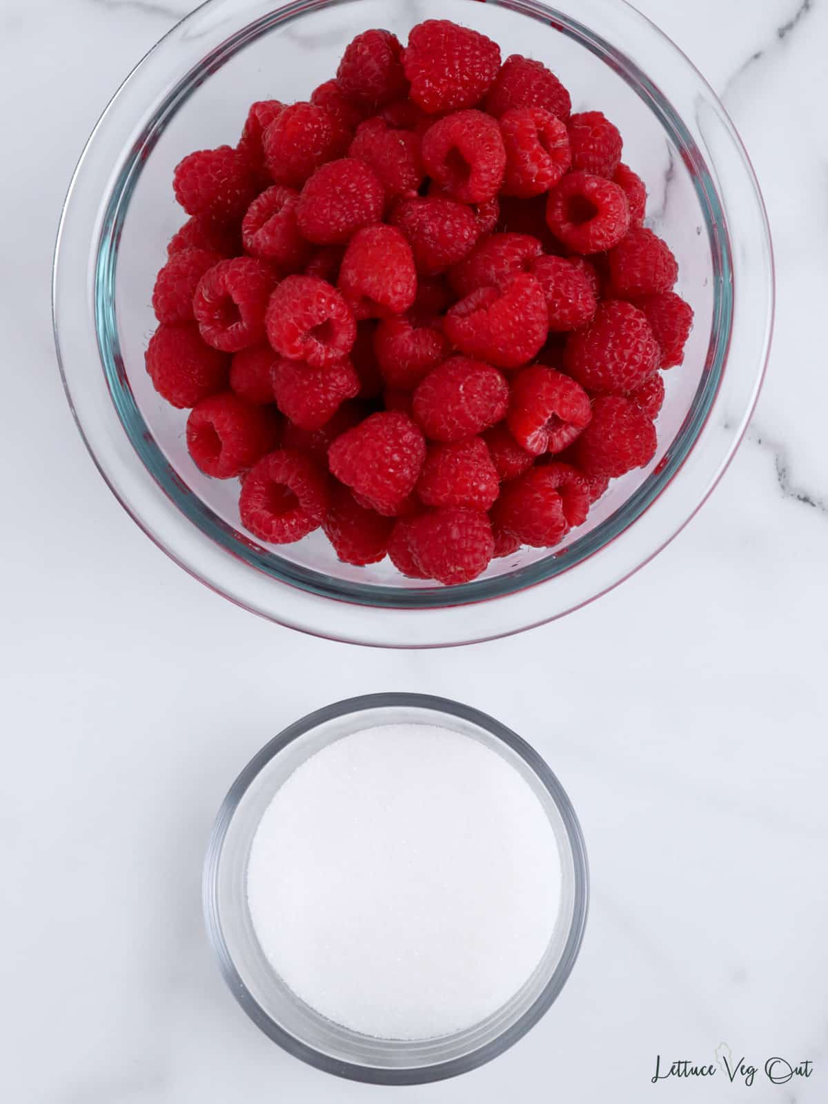 Bowl of fresh raspberries and bowl of sugar.