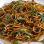 Close up of garlic noodles with edamame and topped with chopped cilantro.