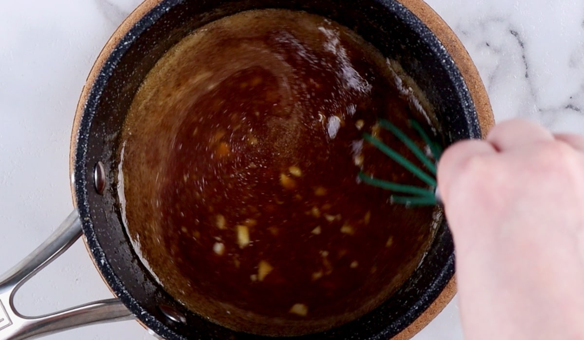 Hand whisking teriyaki sauce in small pot.