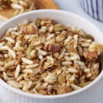 Close up of a bowl filled with oat and puffed rice granola with walnuts and pumpkin seeds.
