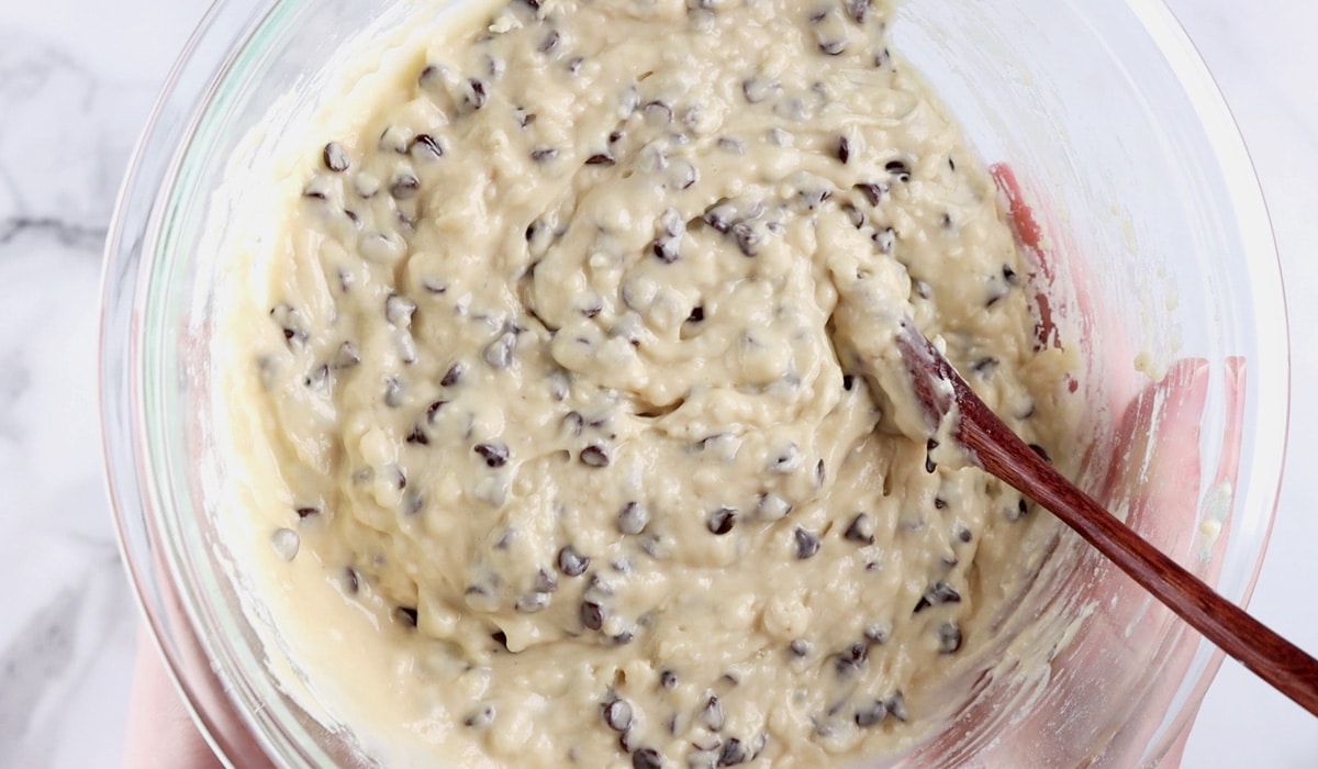 Fully mixed chocolate chip muffin batter in glass mixing bowl.