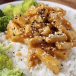 Close up of teriyaki tempeh topped with sesame seeds over rice and broccoli.